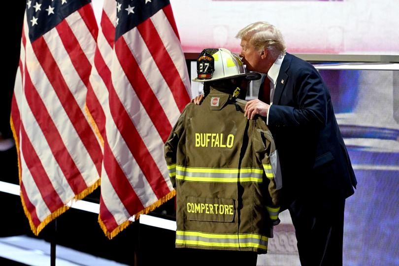 Former US President Donald Trump kisses a firefighter's helmet that belonged to Corey Comperatore, who was fatally shot at a Pennsylvania rally where Trump survived an assassination attempt, during the Republican National Convention (RNC) at the Fiserv Forum in Milwaukee, Wisconsin, US, on Thursday, July 18, 2024. The RNC chairman warned against complacency when his party concludes its official nominating jamboree this week with polls predicting ex-President Donald Trump prevailing over President Joe Biden in the November election. Photographer: David Paul Morris/Bloomberg