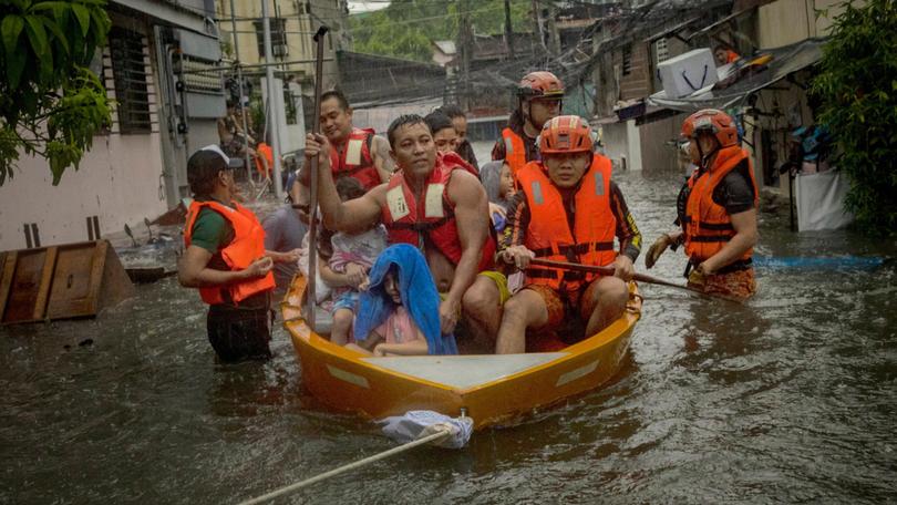 Manila Residents trapped by flooding caused by Typhoon Gaemi and monsoon rains ride a boat to safety.