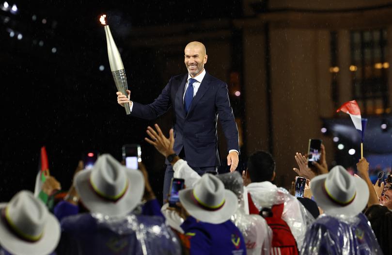 PARIS, FRANCE - JULY26: Zinedine Zidane carries the Olympic torch during the Opening Ceremony of the Olympic Games Paris 2024 on July 26, 2024 in Paris, France. (Photo by Stephanie Lecocq - Pool/Getty Images)