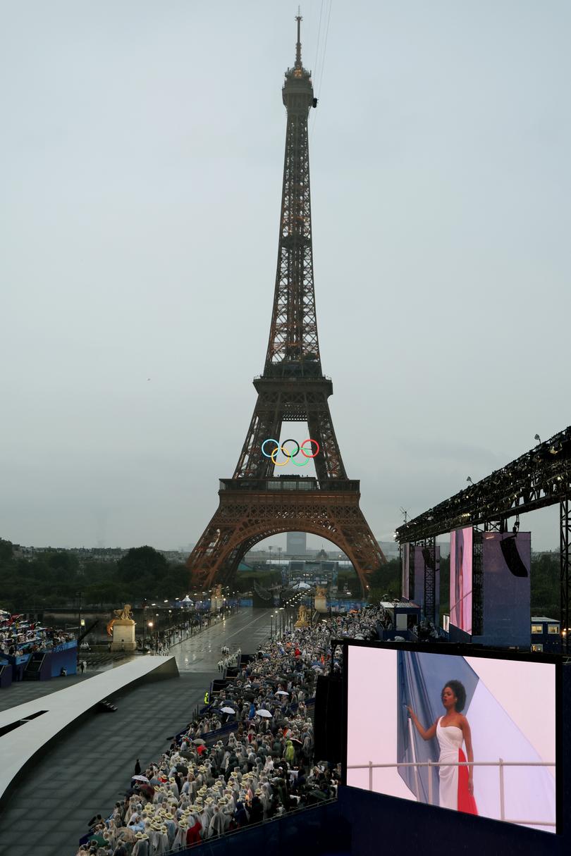 PARIS, FRANCE -  JULY 26: Attendees watch French singer Axelle Saint-Cirel perform the "Marseillaise" on a giant screen during the Opening Ceremony of the Olympic Games Paris 2024 on July 26, 2024 in Paris, France. (Photo by  Ludovic Marin - Pool/Getty Images)