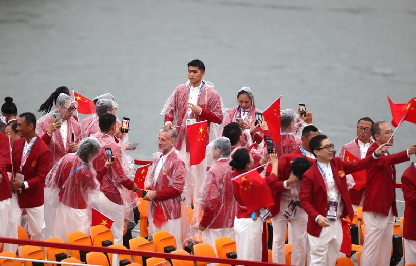 PARIS, FRANCE - JULY 26: Athletes of Team People’s Republic of China wear ponchos as they shelter from the rain on the team boat along the River Seine during the opening ceremony of the Olympic Games Paris 2024 on July 26, 2024 in Paris, France. (Photo by Ryan Pierse/Getty Images)