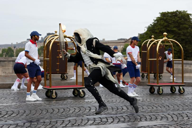 PARIS, FRANCE - JULY 26: A torchbearer runs past Pont Neuf during the opening ceremony of the Olympic Games Paris 2024 on July 26, 2024 in Paris, France. (Photo by Maddie Meyer/Getty Images)