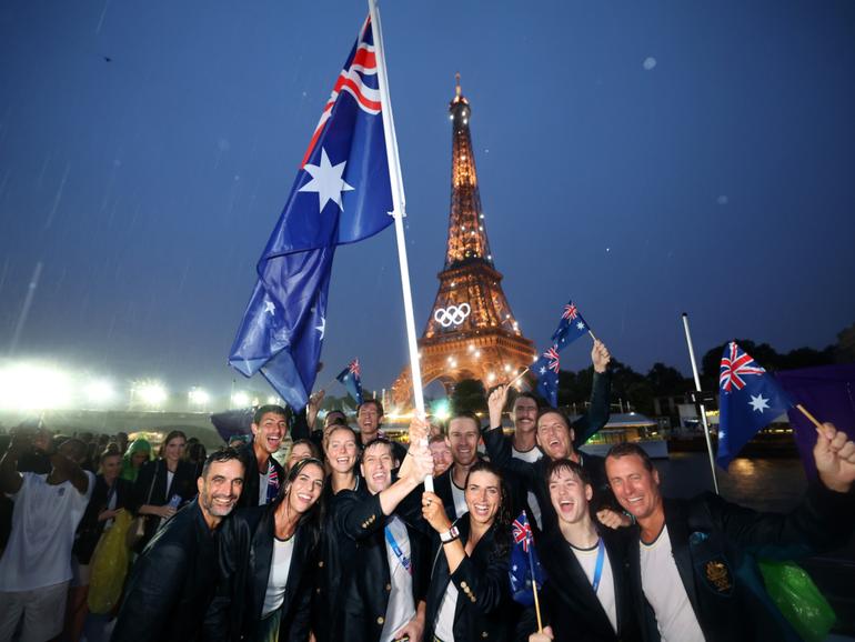Jessica Fox and Eddie Ockenden, Flagbearers of Team Australia, poses for a photo with the illuminated Eiffel Tower while cruising on the River Seine during the athletes’ parade during the opening ceremony of the Olympic Games in Paris.
