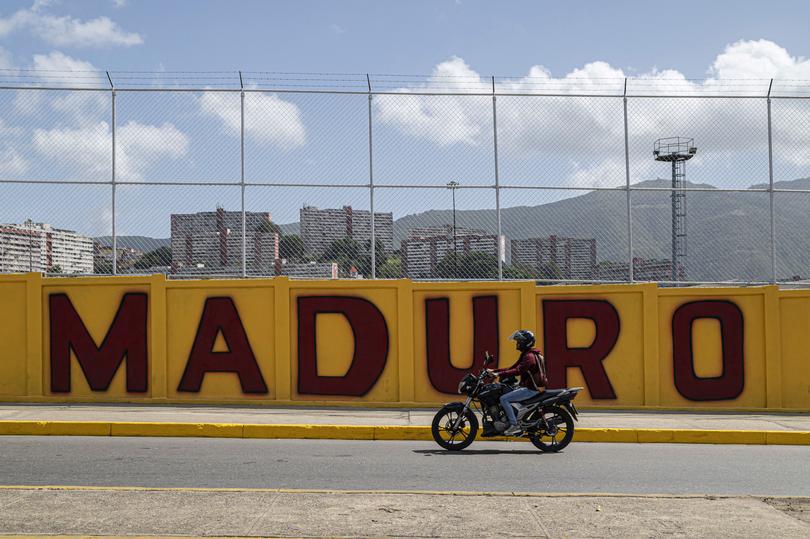 CARACAS, VENEZUELA - JULY 28: A man rides his motorcycle past a Maduro banner during the presidential election on July 28, 2024 in Caracas, Venezuela. Venezuelans go to polls amid a controversial election. Current president of the country Nicolas Maduro seeks the reelection while candidate Edmundo Gonzalez takes part as the leader and face of the opposition. (Photo by Marcelo Perez del Carpio/Getty Images)