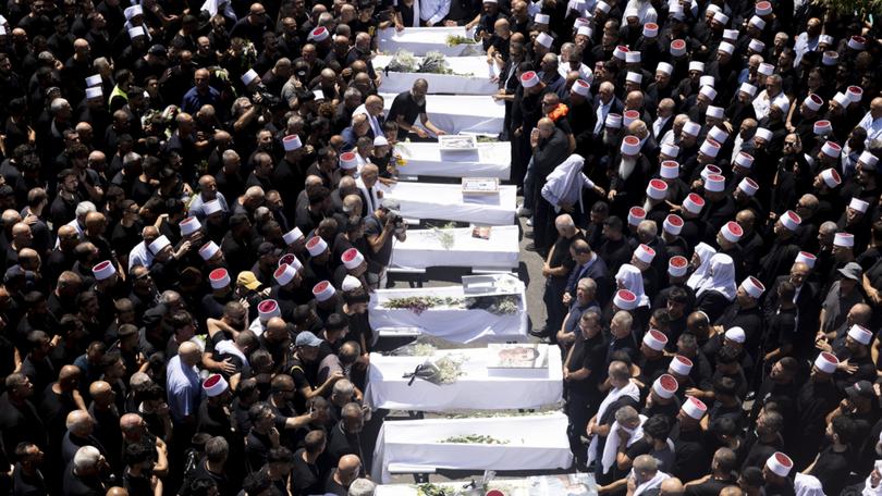 Mourners attend a funeral held for 10 of the victims of the rocket attack in Golan Heights.