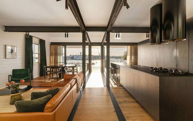 The living and dining area feature industrial-style exposed steel beams that follow the grid of the original cottage.