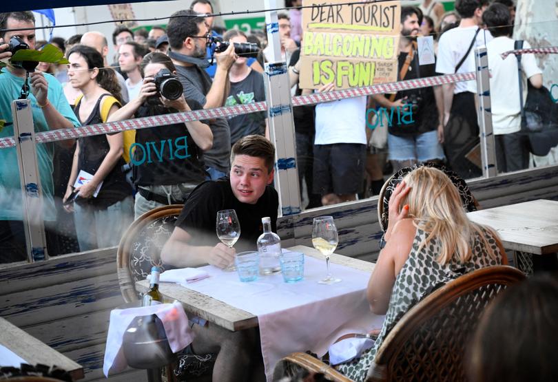 Demonstrators put symbolic cordon on a bar-restaurant window during a protest against mass tourism on Barcelona's Las Ramblas alley.