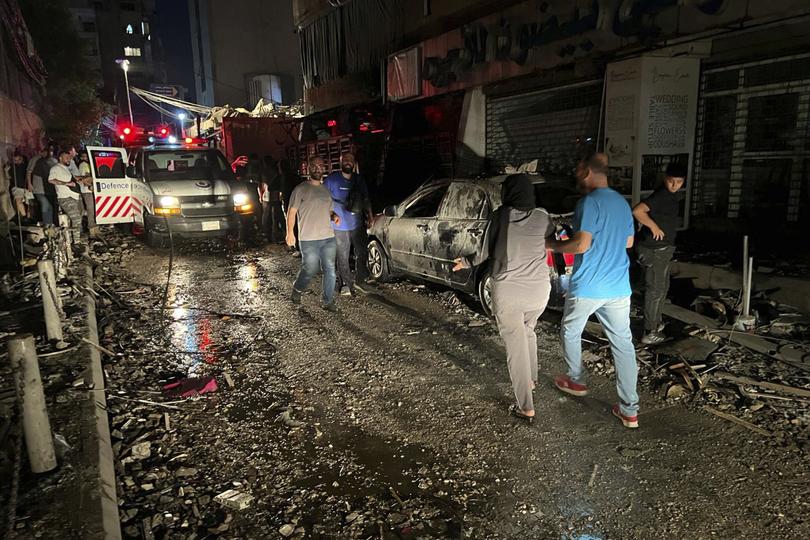 People walk near the building that was hit by an Israeli air strike in the southern suburbs of Beirut, Lebanon, Tuesday, July 30, 2024. 