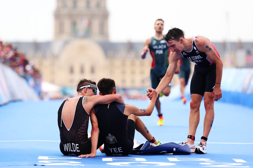 PARIS, FRANCE - JULY 31: Gold medalist Alex Yee of Team Great Britain and Silver medalist Hayden Wilde of Team New Zealand  are congratulated by Pierre le Corre of Team France after crossing the line during Men's Individual Triathlon on day five of the Olympic Games Paris 2024 at Pont Alexandre III on July 31, 2024 in Paris, France. (Photo by Ezra Shaw/Getty Images)