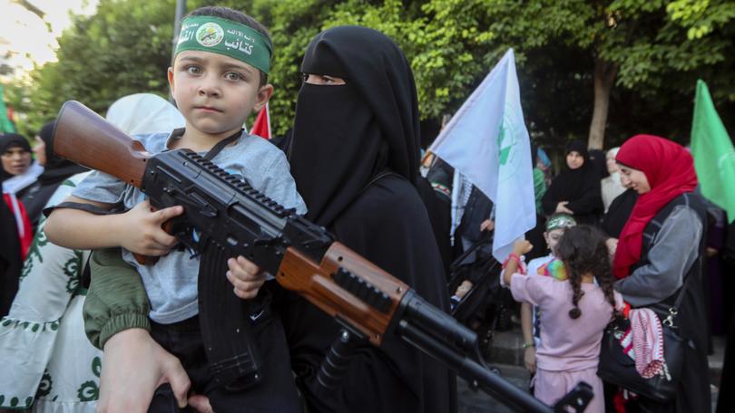 A supporter of the Islamist Hamas movement carries her son, who holds a toy machine gun during a protest in the southern port city of Sidon, Lebanon, 