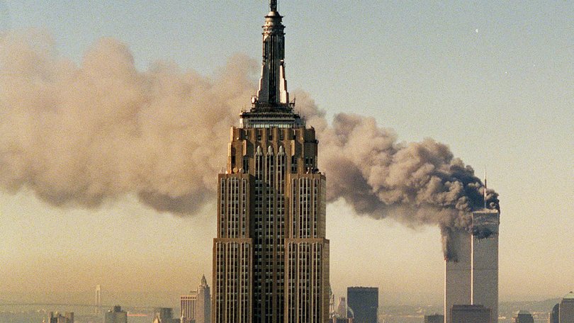 The twin towers of the World Trade Center burn behind the Empire State Building in New York during the September 11 attacks.