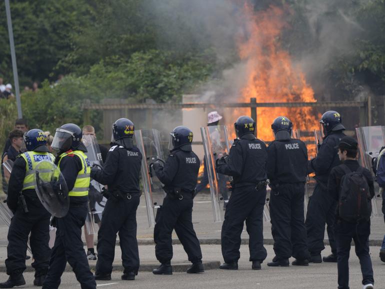 Police officers block protesters as trouble flares during an anti-immigration demonstration outside the Holiday Inn Express in Rotherham, England.