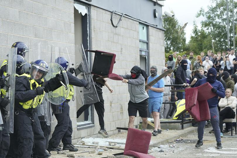 A chair is thrown at police officers as trouble flares during an anti-immigration protest outside the Holiday Inn Express in Rotherham, England.