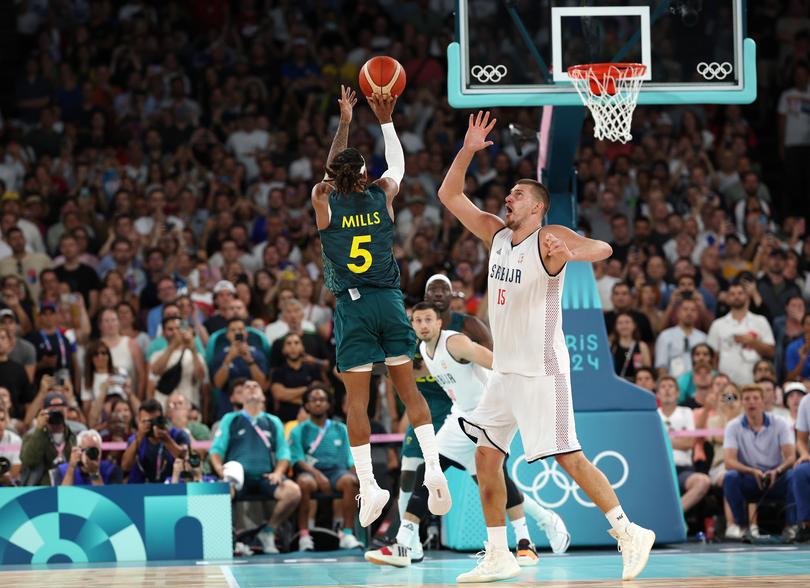 Patty Mills shoots over the head of Nikola Jokic.