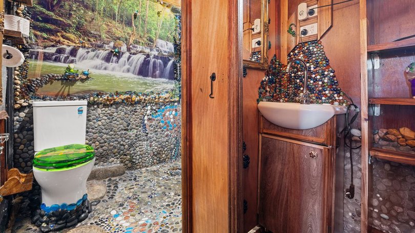 The bathroom has pebbles and glass beads instead of tiles.