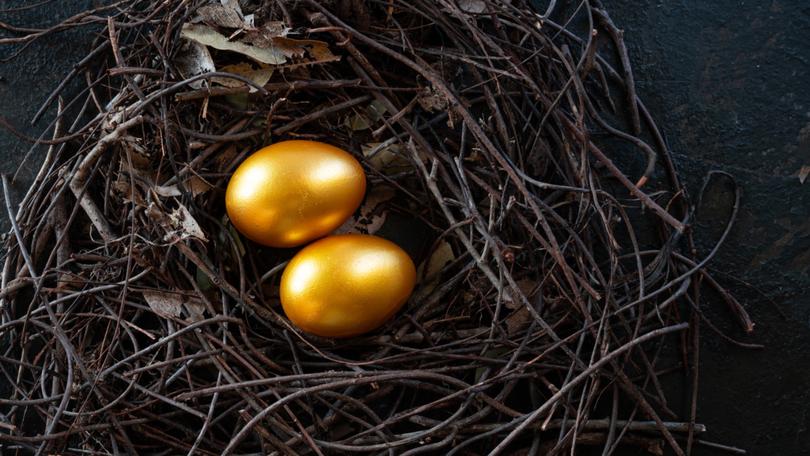 Golden eggs in nest on dark vintage wooden background, golden easter eggs