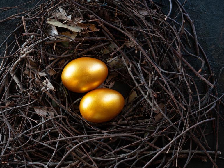 Golden eggs in nest on dark vintage wooden background, golden easter eggs