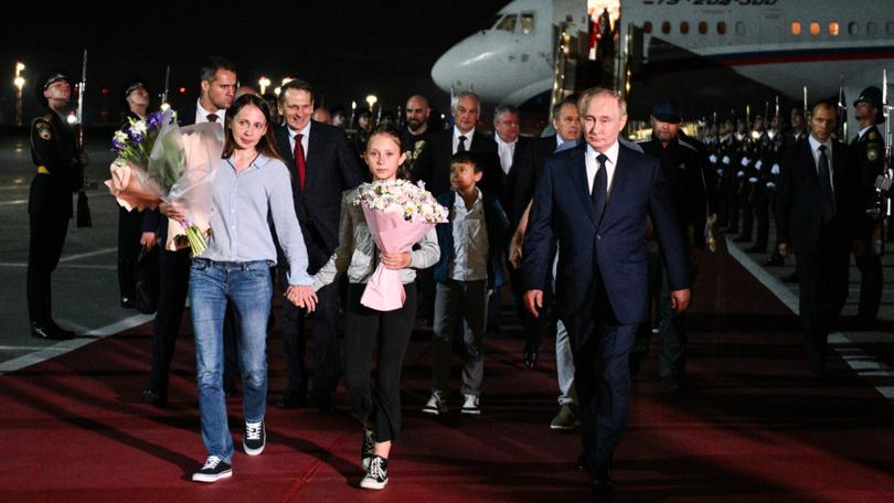 Russia's President Vladimir Putin (R) welcomes Russian citizens released in a prisoner exchange including Vladislav Klyushin.