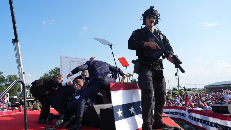 Secret Service agents cover former president Donald Trump after a gunman shot at him during a campaign rally.