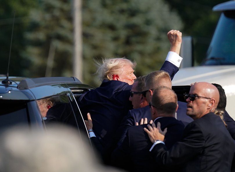 Trump raises his arm as he’s helped into a vehicle after a bullet grazed him during a campaign rally.