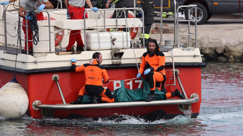 Firefighter teams, Vigili del Fuoco, arrive in Porticello harbor with a recovered body near Palermo.