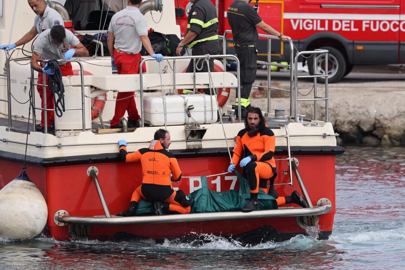 Firefighter teams arrive in Porticello harbour with a recovered body.