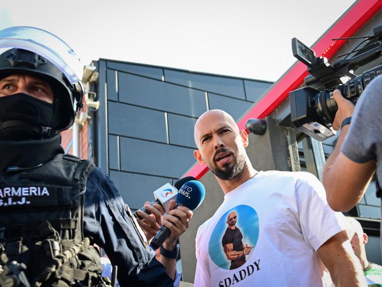 Andrew Tate speaks to journalists as he is brought in for questioning by the Romanian gendarmes.