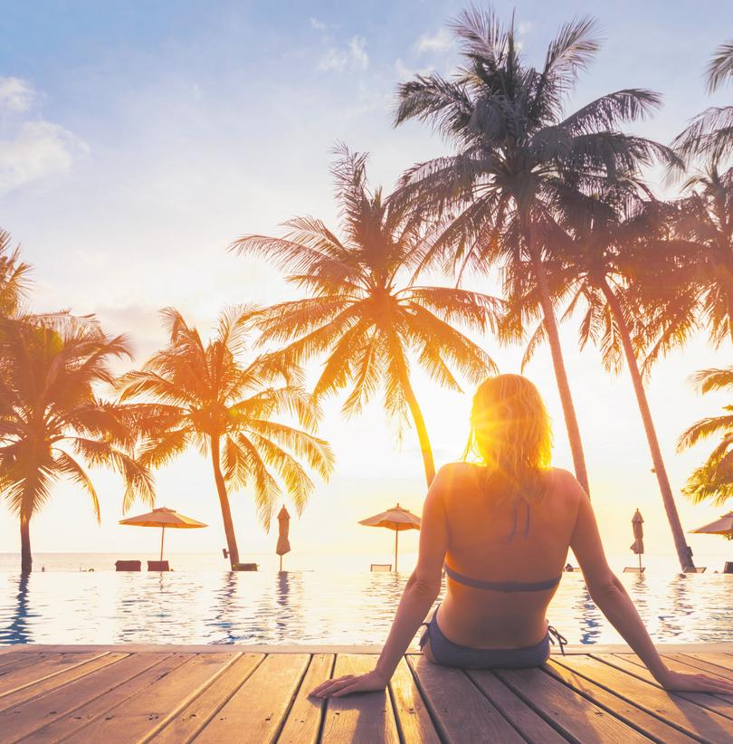 Woman enjoying vacation holidays at luxurious beachfront hotel resort with swimming pool and tropical lansdcape near the beach