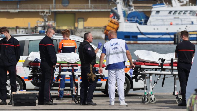 Firefighters, a police officer and a doctor of the SAMU emergency unit stand next to bags containing the bodies of migrants who died after the sinking of a migrant boat attempting to cross the English Channel to England, in Boulogne-sur-Mer, northern France, on September 3, 2024. - Twelve migrants died off the northern French coast on September 3 trying to cross the Channel to England, the French government said, raising an earlier death toll. Interior Minister Gerald Darmanin said on X that two migrants were still missing in the "terrible disaster" and several were injured after their boat ran into trouble, sparking a major rescue operation. (Photo by Denis Charlet / AFP)