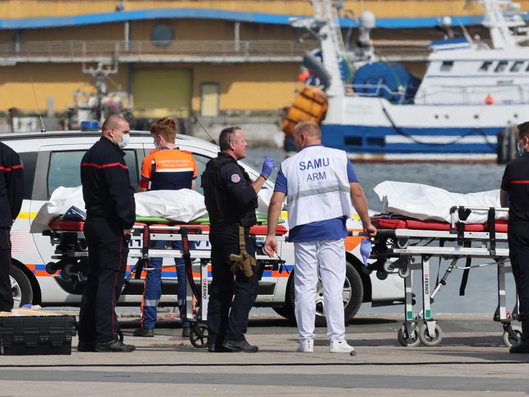 Firefighters, a police officer and a doctor of the SAMU emergency unit stand next to bags containing the bodies of migrants who died after the sinking of a migrant boat attempting to cross the English Channel to England, in Boulogne-sur-Mer, northern France, on September 3, 2024. - Twelve migrants died off the northern French coast on September 3 trying to cross the Channel to England, the French government said, raising an earlier death toll. Interior Minister Gerald Darmanin said on X that two migrants were still missing in the "terrible disaster" and several were injured after their boat ran into trouble, sparking a major rescue operation. (Photo by Denis Charlet / AFP)