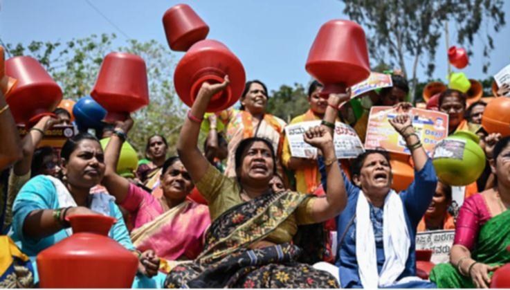 Activists and members of the Bharatiya Janata Party (BJP) hold empty water pots as they shout slogans during a protest against the state government over ongoing severe water crisis, in Bengaluru on March 12, 2024.