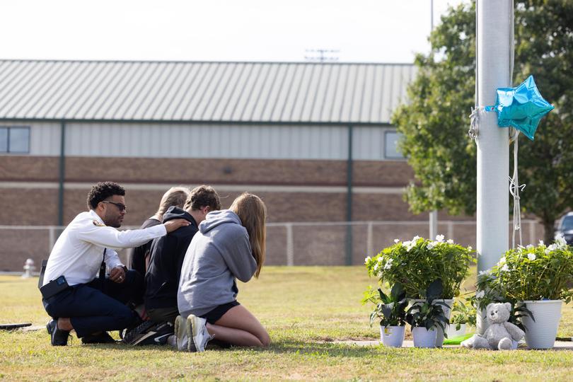 State of Georgia Chaplain Ronald Clark consoles students as they kneel in front of a makeshift memorial at Apalachee High School.