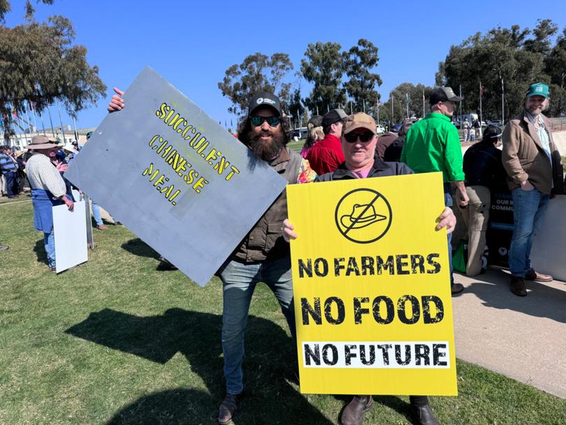 Protesters hold up signs during a National farmers rally outside Parliament in Canberra. 