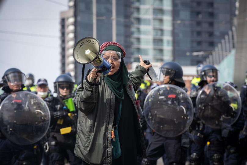 A protester speaks over a megaphone in front of police officers.