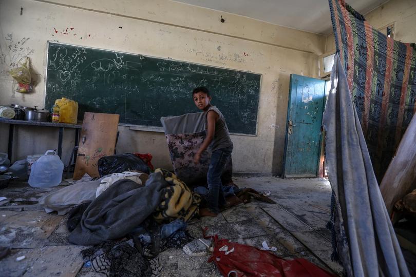 An internally displaced Palestinian boy inspects his family's shelter at a UNRWA-run school.