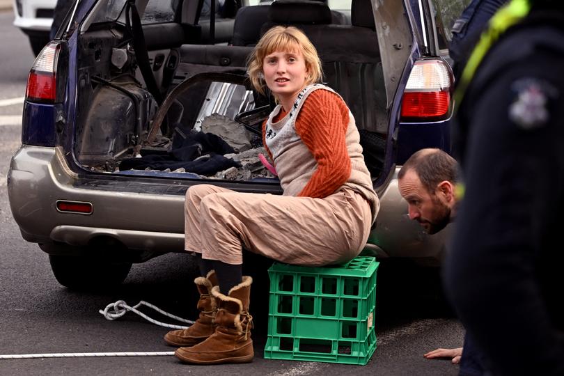 A protestor cemented herself to her car, blocking a road on Friday.