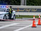 Palm Beach Sheriff officers guard the rear entrance of the Trump International Golf Club.