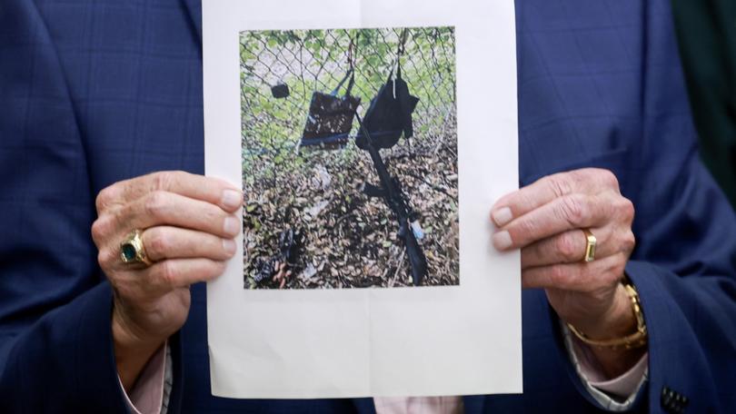 Palm Beach County Sheriff Ric Bradshaw holds a photograph of the rifle and other items found near where a suspect in the attempted assassination attempt was found.