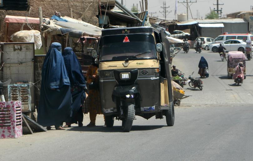 Burqa-clad Afghan women walk on a road in Kandahar in August 2024. 