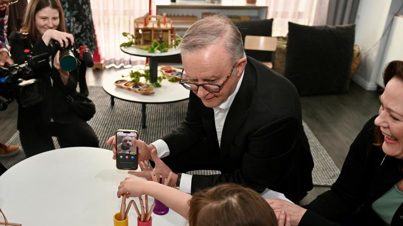 Prime Minister Anthony Albanese shows a photo of his dog, Toto, to children at a Dayton childcare centre during his trip to Perth.