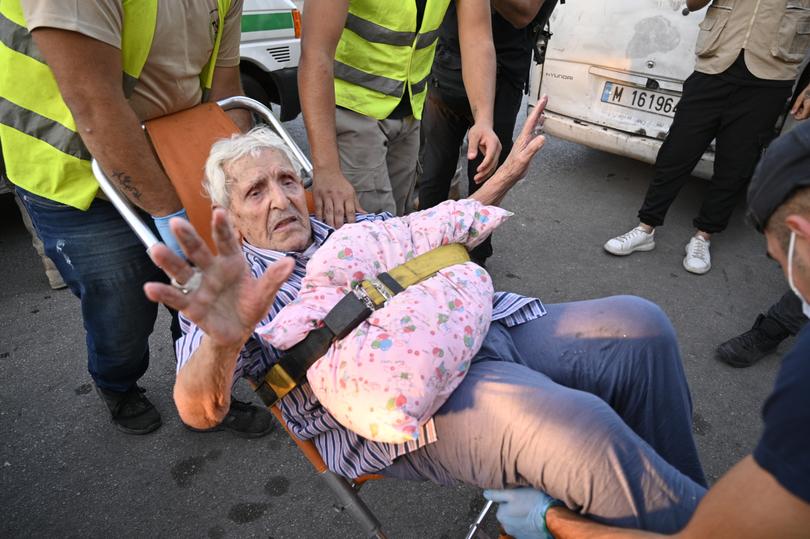 Volunteers assist an elderly man as people who fled southern Lebanon villages arrive at a makeshift shelter at an educational institution in Beirut, Lebanon.