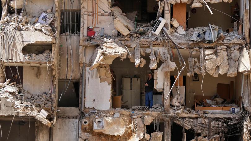 A man watches rescuers sift through the rubble as they search for people still missing at the site of Friday's Israeli strike in Beirut's southern suburbs.