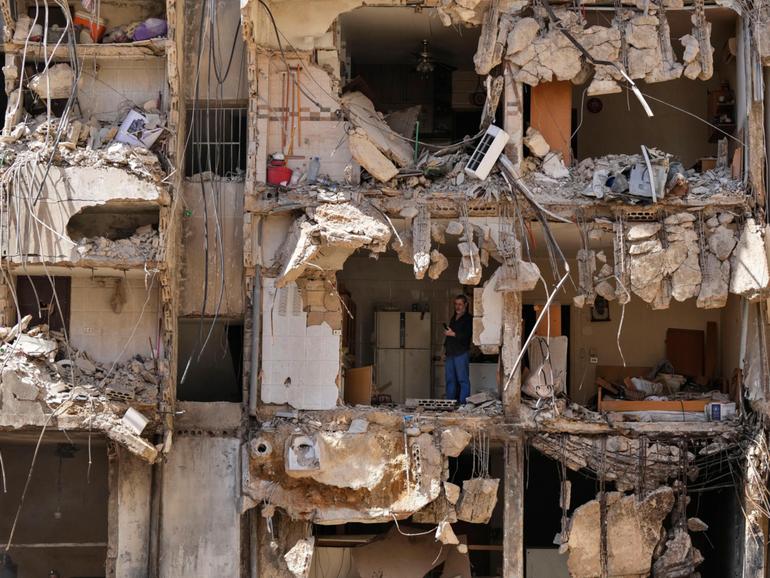 A man watches rescuers sift through the rubble as they search for people still missing at the site of Friday's Israeli strike in Beirut's southern suburbs.