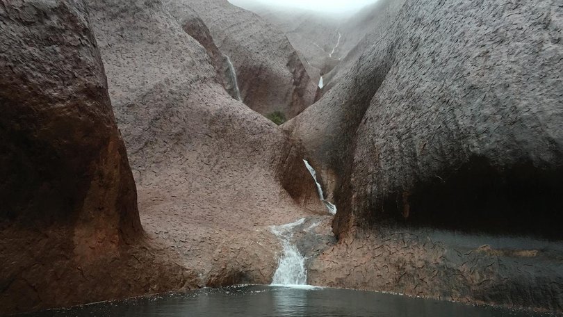 Heavy rain has lashed Uluru in central Australia, leaving water cascading to the ground. (HANDOUT/AAP)