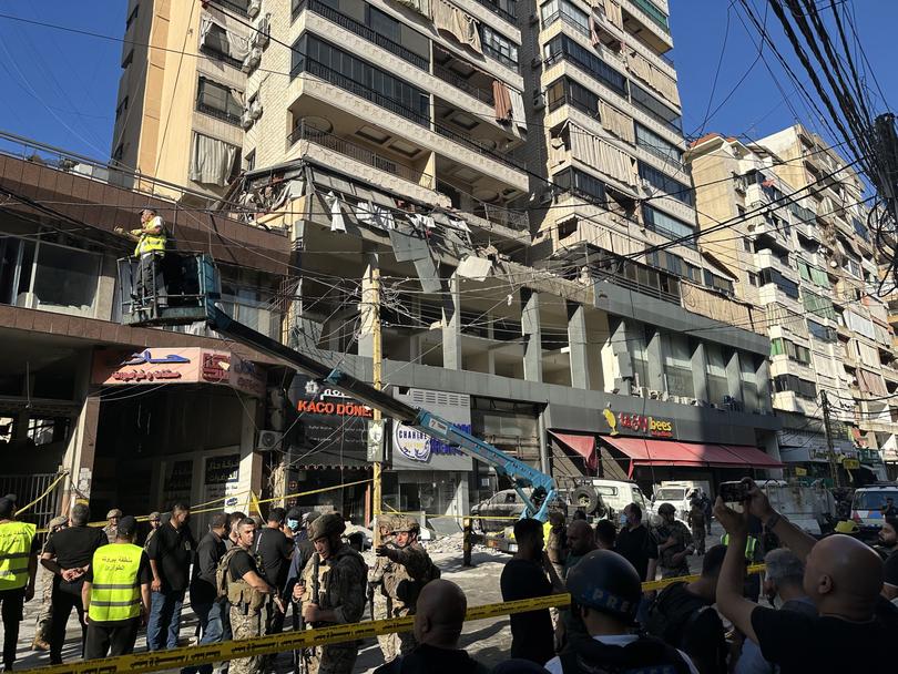 Lebanese army soldiers and residents stand in front of a damaged building in the southern suburb of Beirut following an Israeli raid.