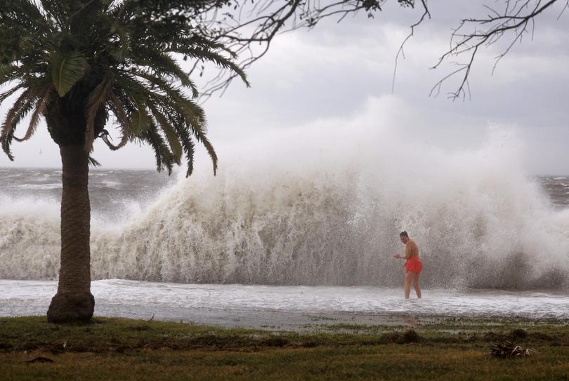 Tanner Flynn stands in shallow water near crashing waves as Hurricane Helene passes offshore on September 26, 2024, in St. Petersburg, Florida.