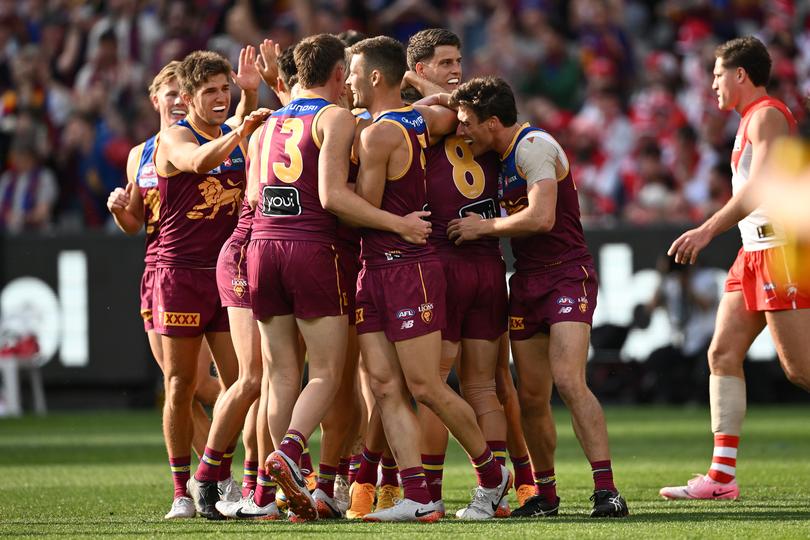 Will Ashcroft of the Lions is congratulated by team mates after kicking a goal.