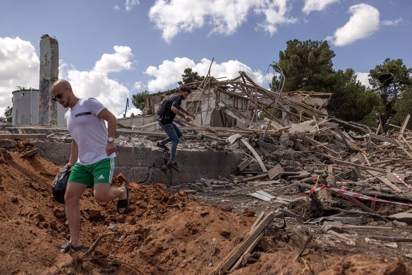 Two men on Wednesday, Oct. 2, 2024, clamber over the wreckage of a building that was destroyed by an Iranian missile attack in Hod Hasharon, near Tel Aviv, Israel. Oil prices jumped about 7% after Iran attacked. 