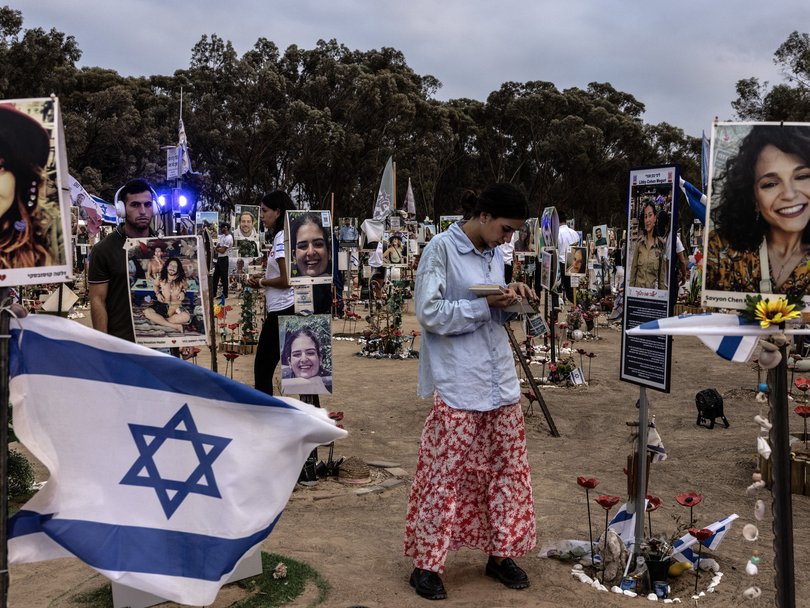 A young woman prays amid portraits affixed to wooden sticks on Oct. 6, the eve of the first anniversary of the deadly Hamas attack on southern Israel, near Kibbutz Reem.