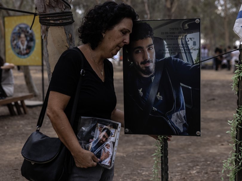 Ruth Madmon, 60, mourns next to a poster of her son Nir, who was killed Oct 7, 2023.